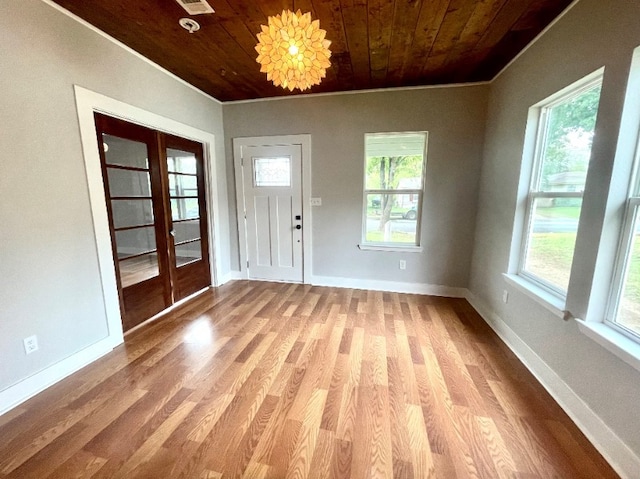 foyer entrance with wooden ceiling, light wood-style flooring, baseboards, ornamental molding, and french doors