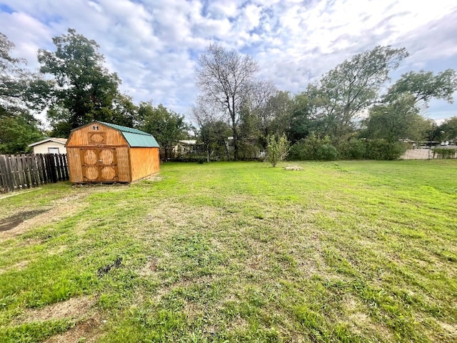 view of yard featuring an outbuilding, a storage unit, and fence