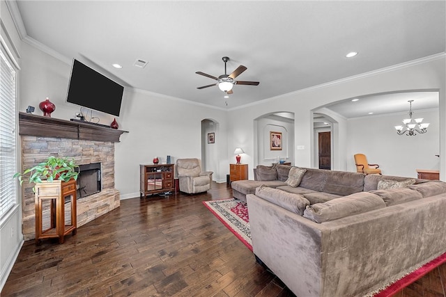 living room with dark wood-type flooring, ornamental molding, a fireplace, and ceiling fan with notable chandelier