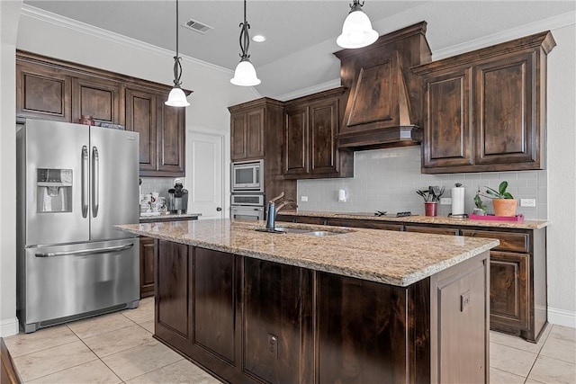 kitchen with dark brown cabinetry, appliances with stainless steel finishes, a kitchen island with sink, and hanging light fixtures