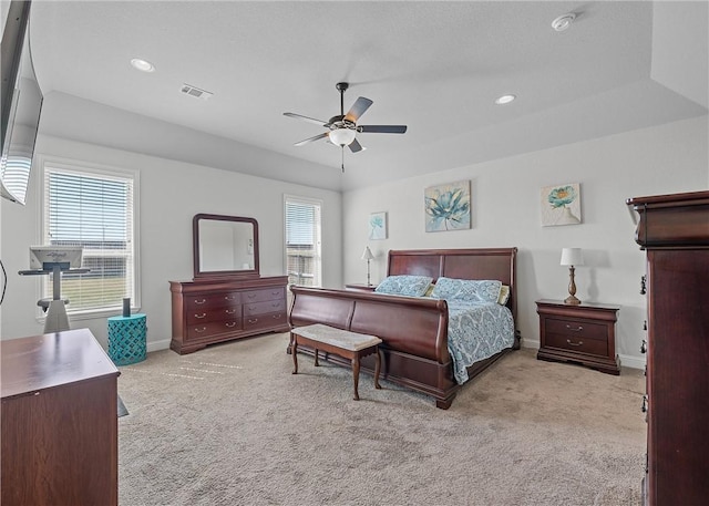 carpeted bedroom with a raised ceiling and ceiling fan