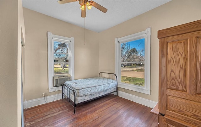 bedroom featuring multiple windows, cooling unit, ceiling fan, and dark wood-type flooring