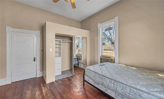 bedroom with a textured ceiling, ceiling fan, cooling unit, dark hardwood / wood-style floors, and a closet