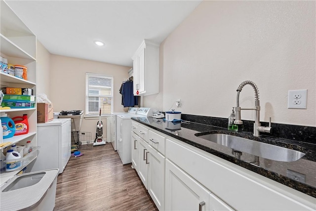 kitchen with sink, dark hardwood / wood-style floors, dark stone countertops, white cabinets, and washer and dryer