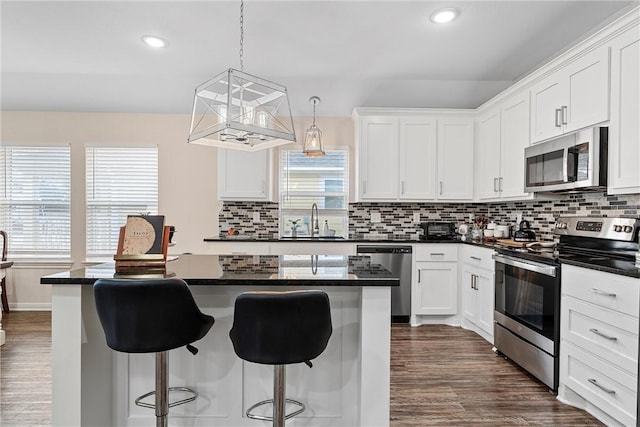 kitchen with white cabinetry, sink, a center island, hanging light fixtures, and stainless steel appliances