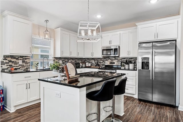 kitchen with white cabinets, a kitchen island, stainless steel appliances, and pendant lighting