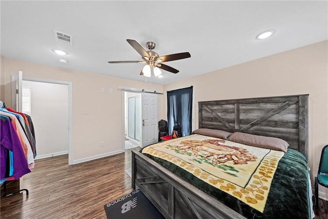 bedroom with hardwood / wood-style flooring, ceiling fan, and a barn door