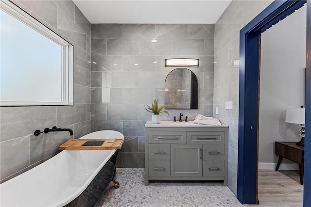 bathroom with a bathing tub, vanity, hardwood / wood-style floors, and tile walls