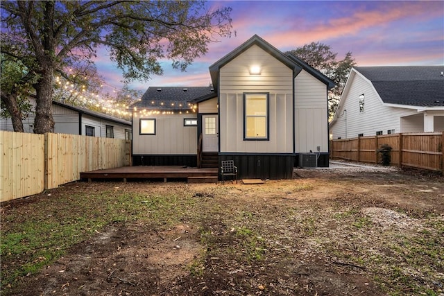 back house at dusk featuring central air condition unit and a wooden deck