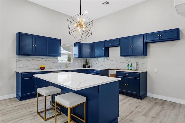 kitchen with blue cabinetry, a center island, and light hardwood / wood-style floors