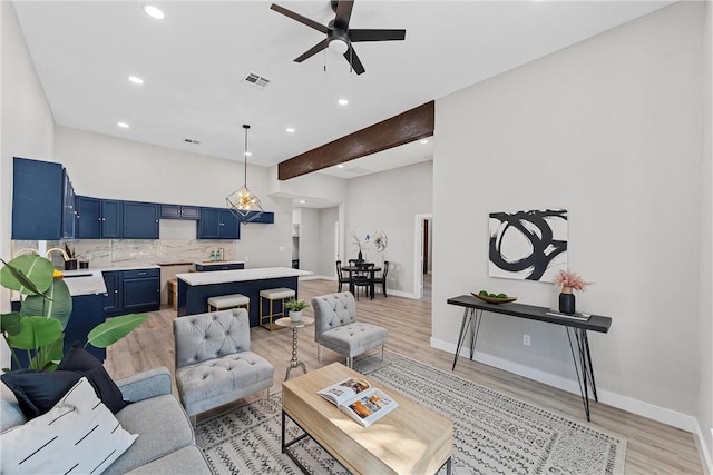 living room with ceiling fan, beam ceiling, light wood-type flooring, and sink