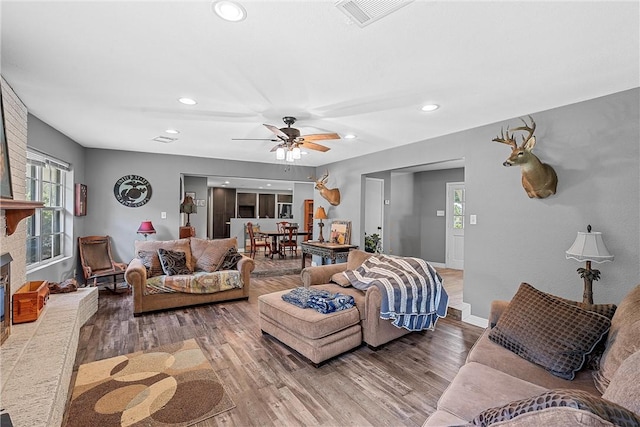 living room featuring ceiling fan, hardwood / wood-style floors, and a brick fireplace