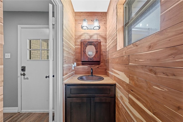 bathroom with wood-type flooring, vanity, and wooden walls