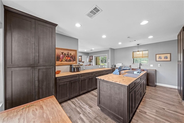 kitchen featuring kitchen peninsula, dark brown cabinets, and light hardwood / wood-style floors