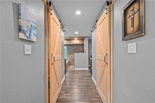 hall with a barn door and dark hardwood / wood-style floors