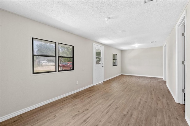 spare room featuring light hardwood / wood-style flooring and a textured ceiling