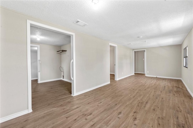 unfurnished room with hardwood / wood-style flooring and a textured ceiling