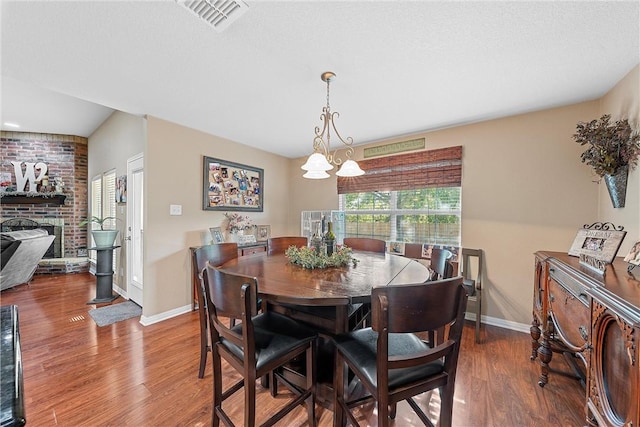 dining area with hardwood / wood-style floors, a brick fireplace, and a chandelier