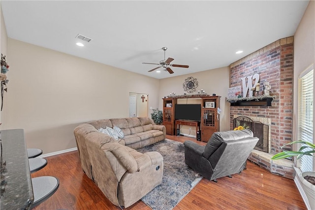 living room with ceiling fan, a fireplace, and dark wood-type flooring