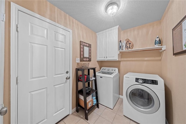 laundry area featuring cabinets, independent washer and dryer, a textured ceiling, and light tile patterned floors