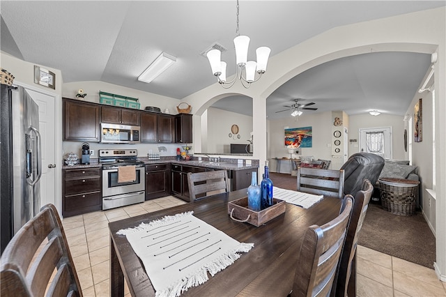 kitchen featuring pendant lighting, light tile patterned flooring, stainless steel appliances, and vaulted ceiling