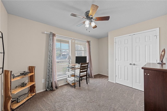 home office featuring dark colored carpet, ceiling fan, and a textured ceiling