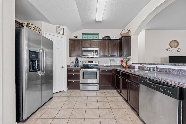 kitchen featuring light tile patterned floors, lofted ceiling, sink, and appliances with stainless steel finishes