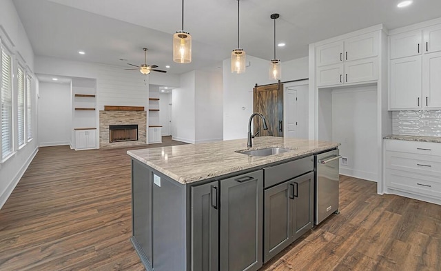 kitchen with a barn door, light stone counters, white cabinetry, and sink