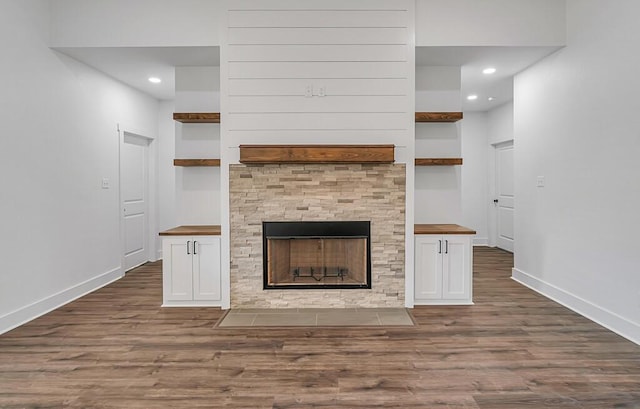 unfurnished living room featuring a fireplace, dark wood-type flooring, and built in features