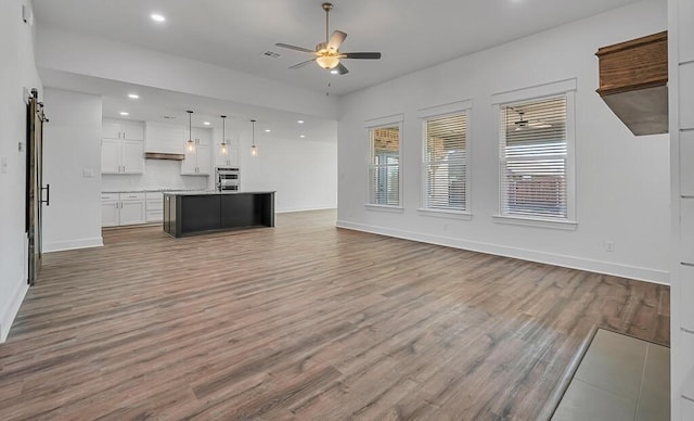 unfurnished living room with ceiling fan and hardwood / wood-style floors