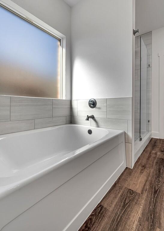 bathroom featuring hardwood / wood-style floors, independent shower and bath, and tile walls