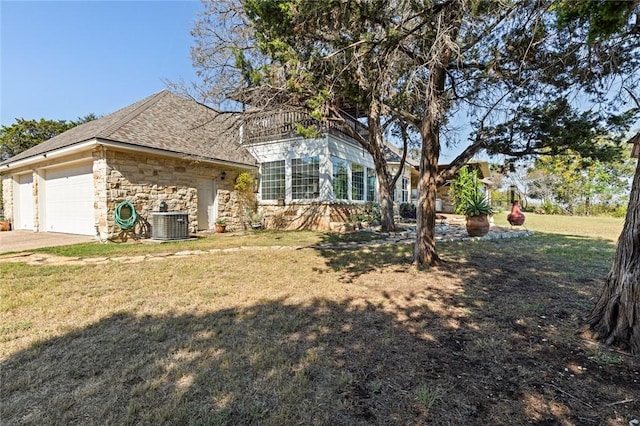 view of front of home with cooling unit, a garage, and a front yard