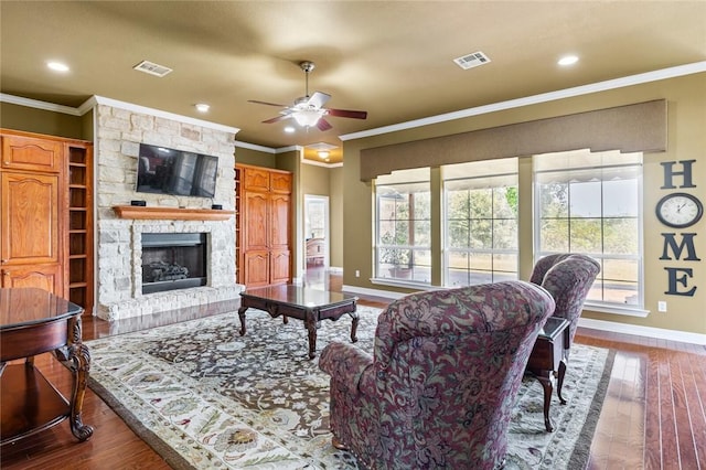 living room featuring hardwood / wood-style floors, ceiling fan, ornamental molding, and a fireplace