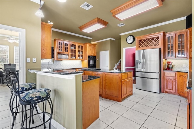 kitchen featuring a breakfast bar area, backsplash, a center island, and black appliances