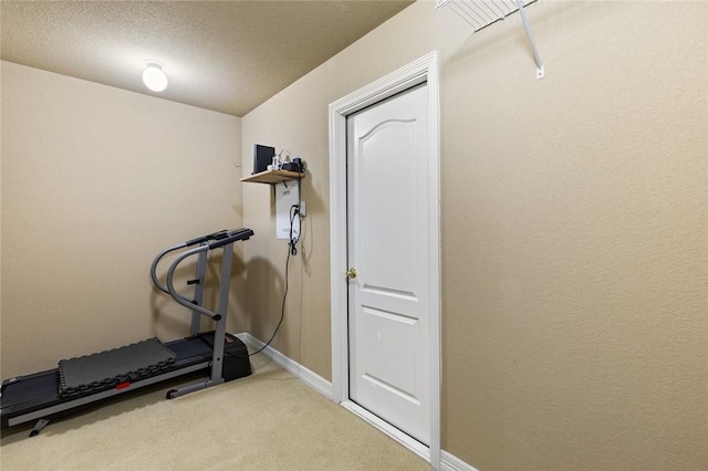 exercise room with a textured ceiling and light colored carpet