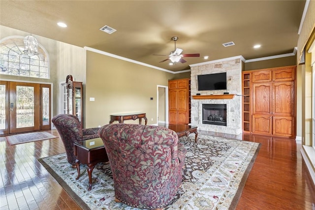 living room with crown molding, a fireplace, ceiling fan with notable chandelier, and dark hardwood / wood-style floors