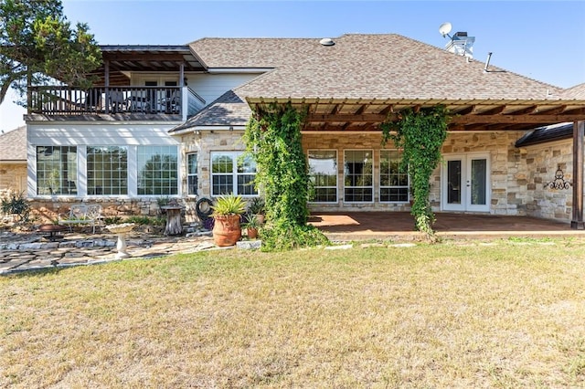 back of property with a lawn, a balcony, and french doors