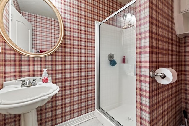 bathroom featuring a shower with door and sink