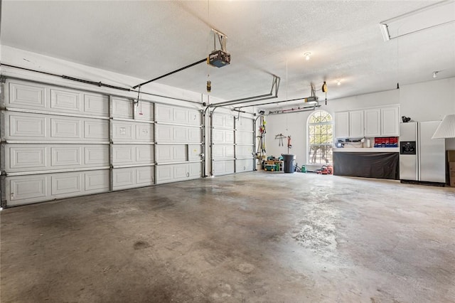 garage with stainless steel fridge with ice dispenser and a garage door opener