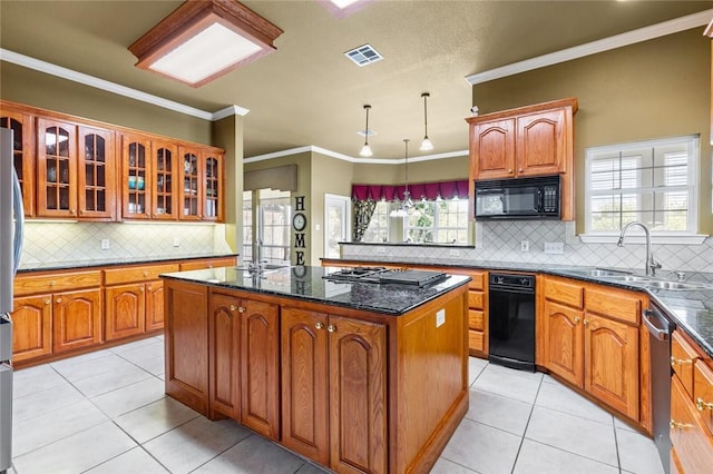 kitchen featuring black appliances, a center island, sink, and a wealth of natural light