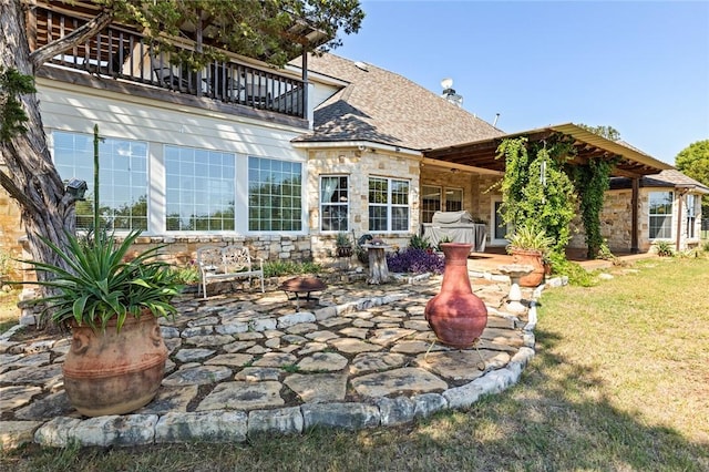 view of patio featuring a balcony and an outdoor fire pit