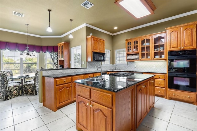 kitchen featuring a center island with sink, black appliances, a healthy amount of sunlight, and sink