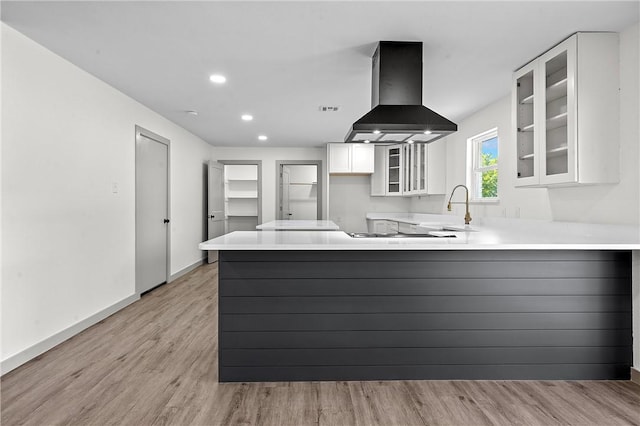 kitchen featuring ventilation hood, white cabinets, sink, light hardwood / wood-style floors, and kitchen peninsula