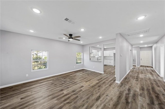 unfurnished living room with ceiling fan and dark wood-type flooring