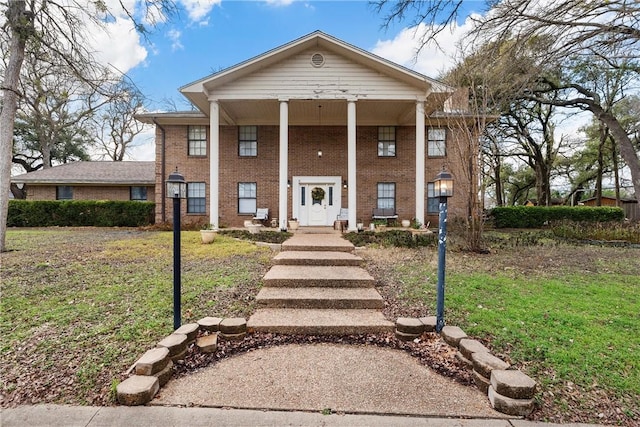 greek revival inspired property featuring covered porch and a front yard