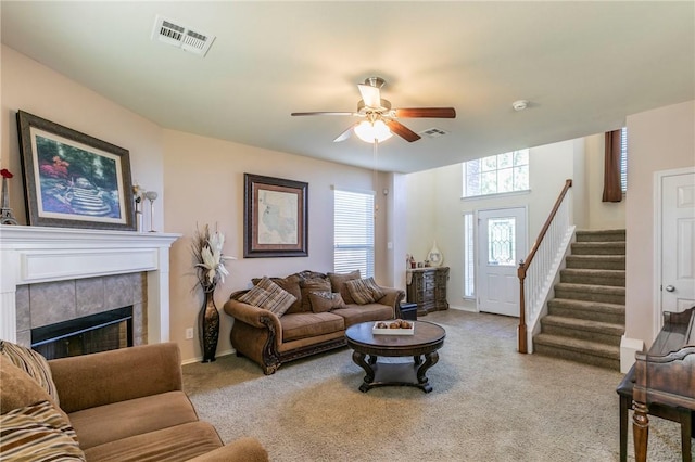 carpeted living room featuring a tile fireplace and ceiling fan