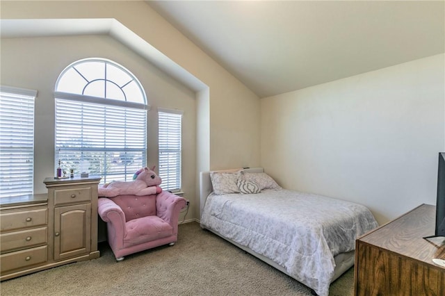 bedroom with light colored carpet, vaulted ceiling, and multiple windows