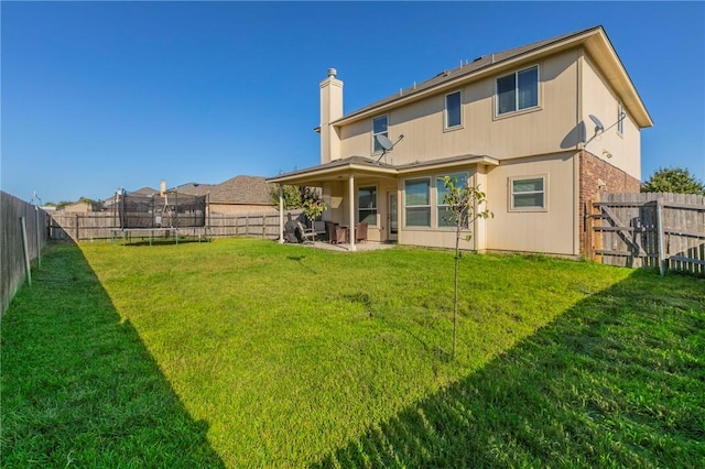 back of property featuring a yard, a trampoline, and a patio