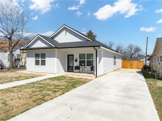 view of front of house featuring a shingled roof, covered porch, board and batten siding, driveway, and a front lawn