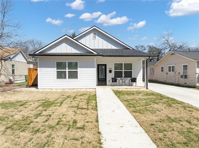 bungalow with board and batten siding, covered porch, and a front lawn